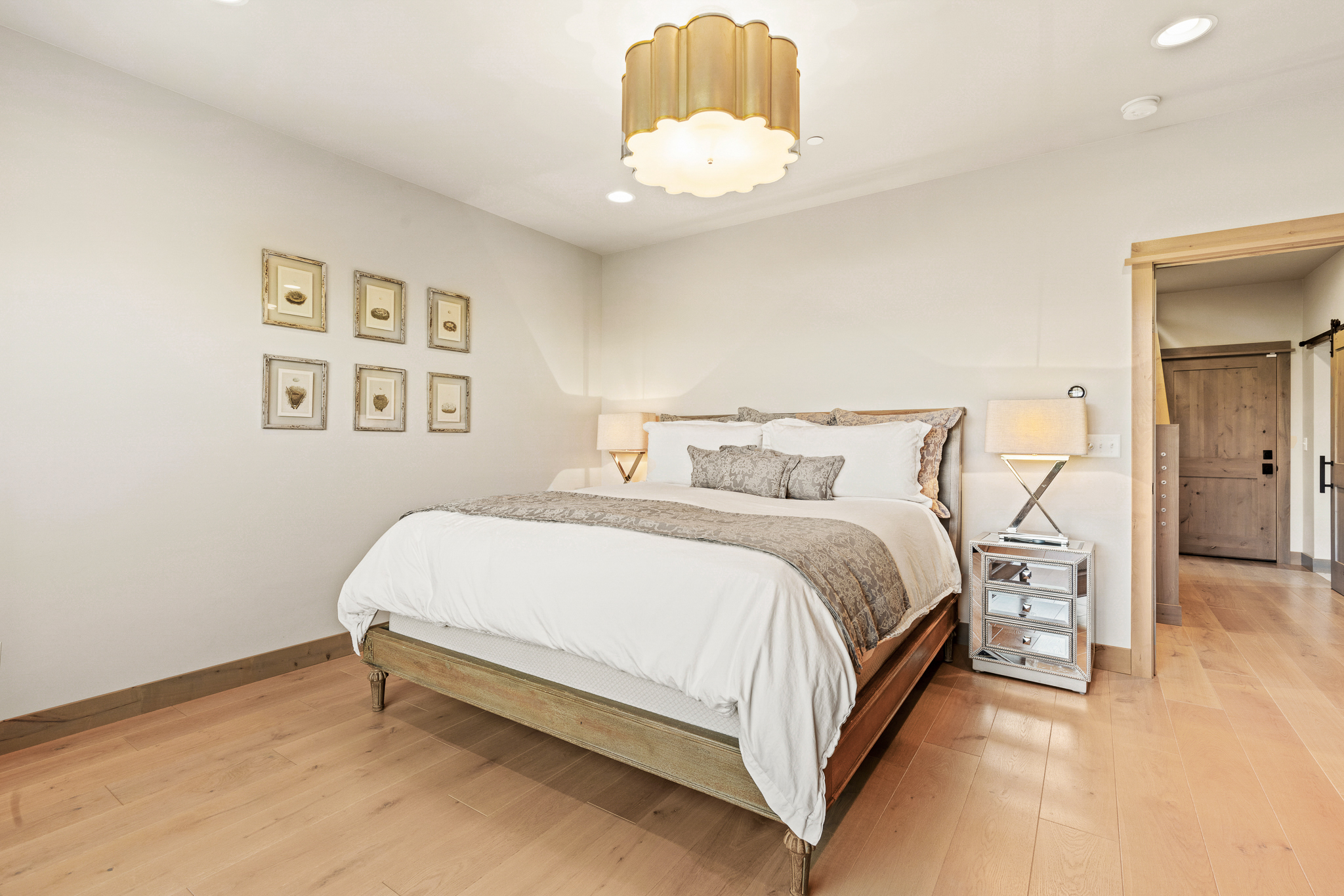 Primary bedroom at 58 Waylon Way in Bozeman’s Home 40 community featuring natural wood floors, designer lighting, neutral palette, and custom luxury finishes.